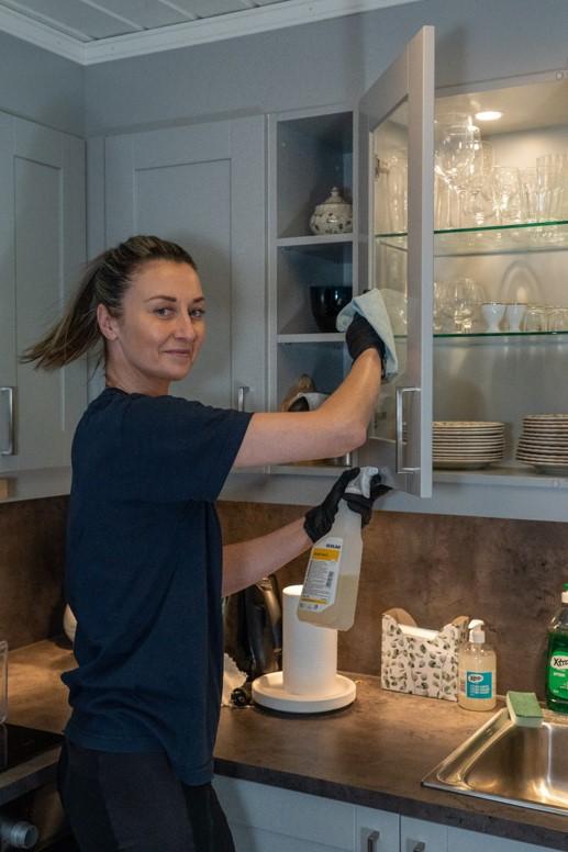 Kvinne med brunt hår vasker kjøkkenskap